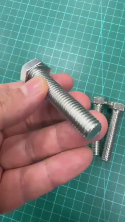 손으로 든 육각 볼트의 머리와 나사산